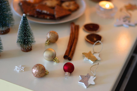 Various Christmas decorations, cookies, chocolate, nuts and tangerines, wine glasses and lit candles on the table. Holiday hygge at home. Selective focus.の写真素材