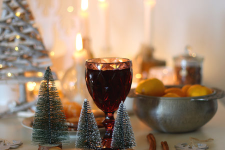 Various Christmas decorations, cookies, chocolate, nuts and tangerines, wine glasses and lit candles on the table. Holiday hygge at home. Selective focus.の写真素材