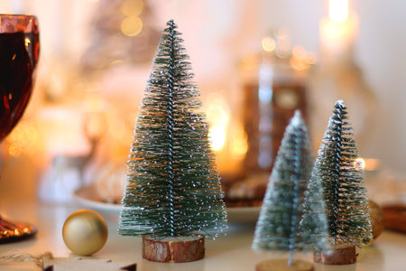 Various Christmas decorations, cookies, chocolate, nuts and tangerines, wine glasses and lit candles on the table. Holiday hygge at home. Selective focus.の写真素材