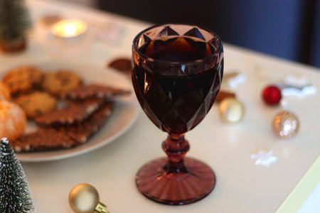 Various Christmas decorations, cookies, chocolate, nuts and tangerines, wine glasses and lit candles on the table. Holiday hygge at home. Selective focus.の写真素材