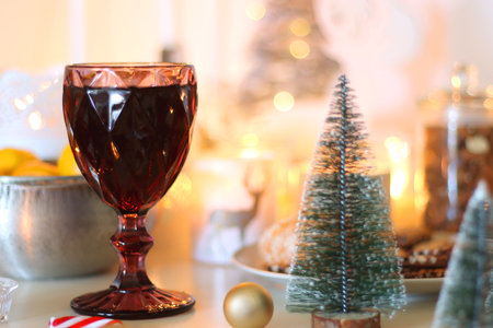 Various Christmas decorations, cookies, chocolate, nuts and tangerines, wine glasses and lit candles on the table. Holiday hygge at home. Selective focus.の写真素材