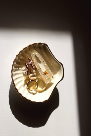 White shell shaped trinket with gold and beige accessories. Top view, white background.の写真素材
