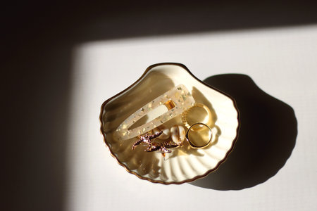 White shell shaped trinket with gold and beige accessories. Top view, white background.の写真素材