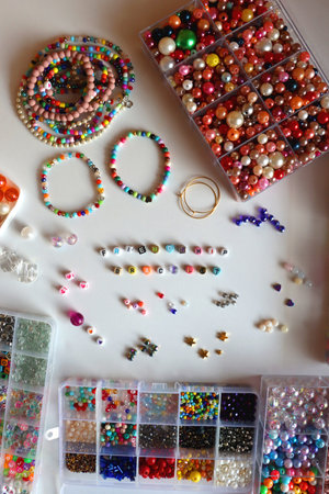Friendship bracelet spelled with letter beads. Colorful handmade bracelets and various jewelry making supplies. Top view, white background.の写真素材