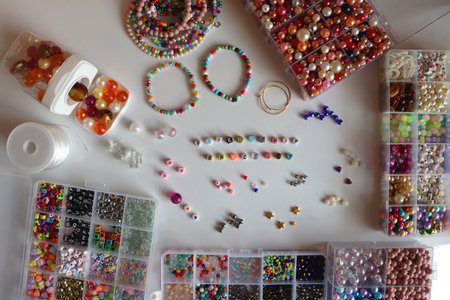 Friendship bracelet spelled with letter beads. Colorful handmade bracelets and various jewelry making supplies. Top view, white background.の写真素材