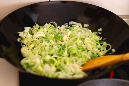 Sauteing chopped leek slices in a wok. Selective focus.の写真素材