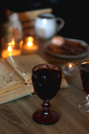 Books, lit candles, red wine, snacks and various deocration on the table. Dark academia or Halloween concept. Selective focus.の写真素材