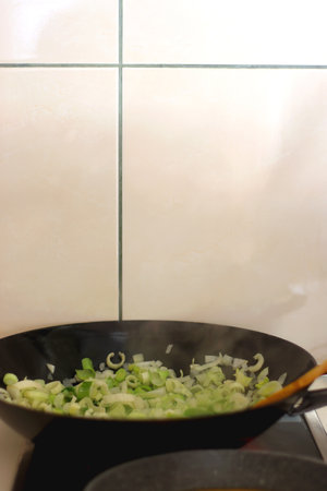 Sauteing chopped leek slices in a wok. Selective focus.の写真素材