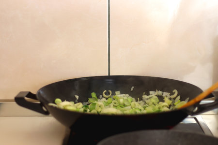 Sauteing chopped leek slices in a wok. Selective focus.の写真素材