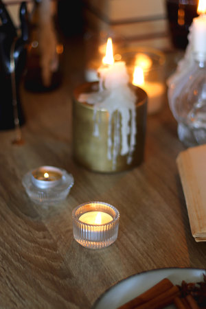 Books, lit candles, red wine, snacks and various deocration on the table. Dark academia or Halloween concept. Selective focus.の写真素材