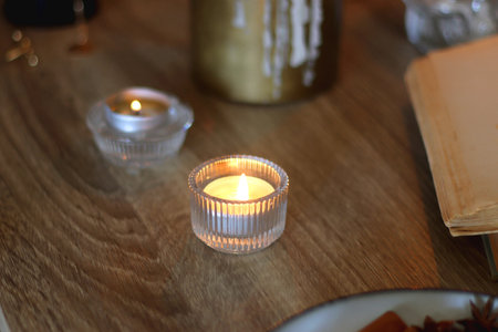 Books, lit candles, red wine, snacks and various deocration on the table. Dark academia or Halloween concept. Selective focus.の写真素材