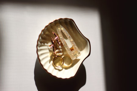 White shell shaped trinket with gold and beige accessories. Top view, white background.の写真素材