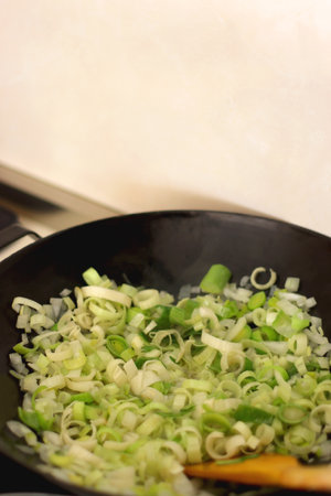 Sauteing chopped leek slices in a wok. Selective focus.の写真素材