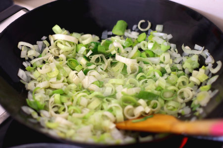 Sauteing chopped leek slices in a wok. Selective focus.の写真素材