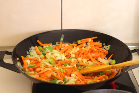Sauteing chopped leek and carrot slices in a wok. Selective focus.の写真素材