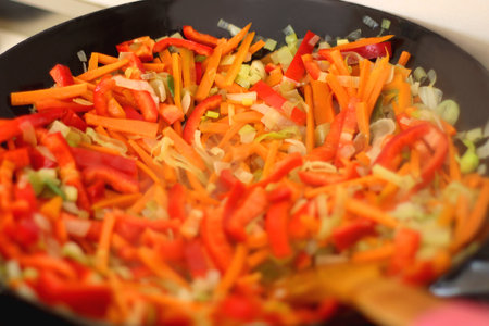 Stir frying chopped leek, carrots and red bell peppers in a wok. Selective focus.の写真素材