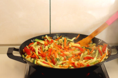 Stir frying chopped leek, zucchinis, carrots and red bell peppers in a wok. Selective focus.の写真素材