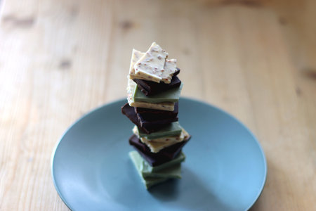 Pile of various chocolate pieces on a plate. Dark, white and matcha chocolate. Selective focus.の写真素材