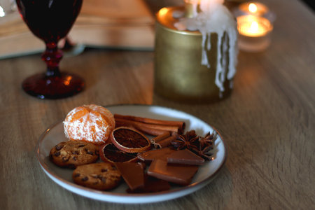 Books, lit candles, red wine, snacks and various deocration on the table. Dark academia or Halloween concept. Selective focus.の写真素材