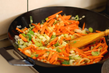 Sauteing chopped leek and carrot slices in a wok. Selective focus.の写真素材