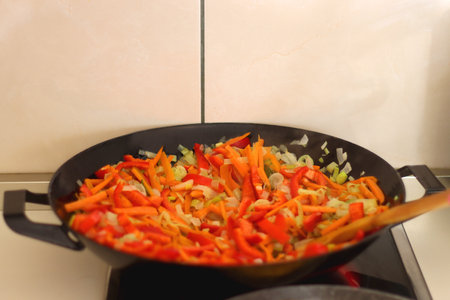 Stir frying chopped leek, carrots and red bell peppers in a wok. Selective focus.の写真素材