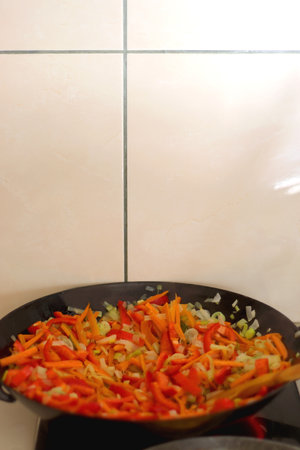 Stir frying chopped leek, carrots and red bell peppers in a wok. Selective focus.の写真素材