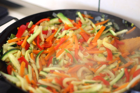 Stir frying chopped leek, zucchinis, carrots and red bell peppers in a wok. Selective focus.の写真素材