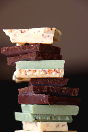 Pile of various chocolate pieces on a plate. Dark, white and matcha chocolate. Selective focus.の写真素材
