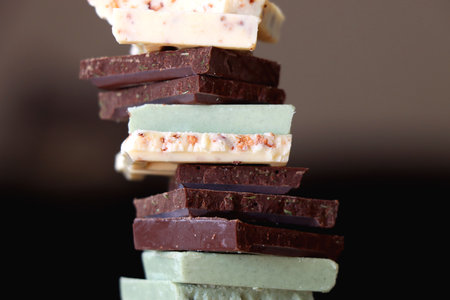 Pile of various chocolate pieces on a plate. Dark, white and matcha chocolate. Selective focus.の写真素材