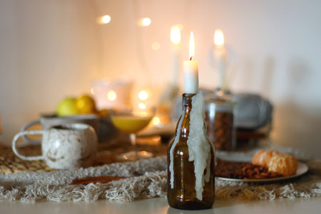 Books, e-reader, tea, orange juice, fruit, snacks, yarn, blanket and lit candles on the table. Autumn or winter hygge at home. Selective focus.の写真素材