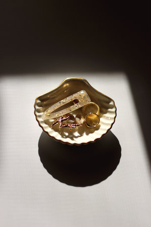 White shell shaped trinket with gold and beige accessories. Selective focus, white background.の写真素材