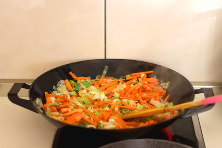 Sauteing chopped leek and carrot slices in a wok. Selective focus.の写真素材