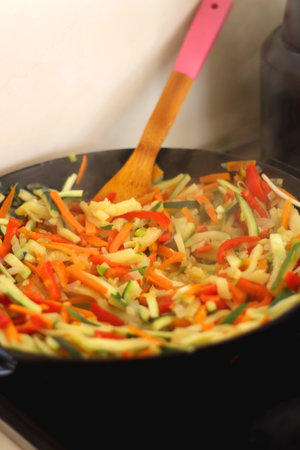 Stir frying chopped leek, zucchinis, carrots and red bell peppers in a wok. Selective focus.の写真素材