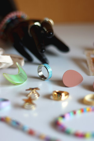Hand figurine, sunglasses, gold jewelry, colorful bead jewelry, statement rings and various hair accessories on the white table. Selective focus.の写真素材