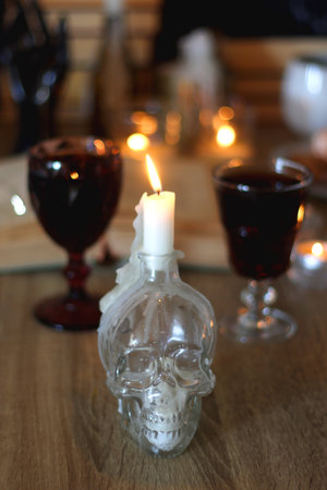 Books, lit candles, red wine, snacks and various decoration on the table. Dark academia or Halloween concept. Selective focus.の写真素材