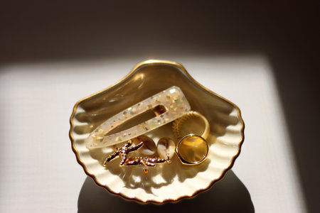 White shell shaped trinket with gold and beige accessories. Selective focus, white background.の写真素材