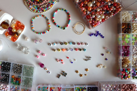 Friendship bracelet spelled with letter beads. Colorful handmade bracelets and various jewelry making supplies. Top view, white background.の写真素材