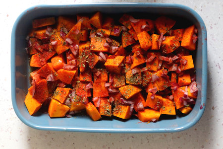 Sheet pan with pieces of butternut squash, onion, herbs and spices. Preparing pumpkin for a roast. Top view.の写真素材
