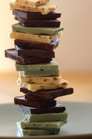 Pile of various chocolate pieces on a plate. Dark, white and matcha chocolate. Selective focus.の写真素材