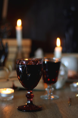 Books, lit candles, red wine, snacks and various decoration on the table. Dark academia or Halloween concept. Selective focus.の写真素材