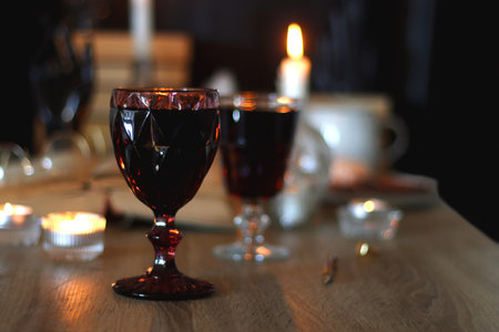 Books, lit candles, red wine, snacks and various deocration on the table. Dark academia or Halloween concept. Selective focus.の写真素材