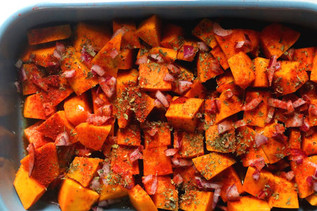 Sheet pan with pieces of butternut squash, onion, herbs and spices. Preparing pumpkin for a roast. Top view.の写真素材