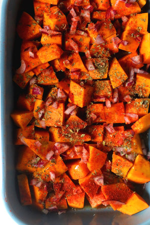 Sheet pan with pieces of butternut squash, onion, herbs and spices. Preparing pumpkin for a roast. Top view.の写真素材