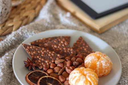 Orange juice, fruit, snacks, and chocolate on the plate. Autumn or winter hygge at home. Selective focus.の写真素材