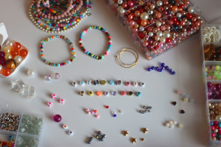 Friendship bracelet spelled with letter beads. Colorful handmade bracelets and various jewelry making supplies. Selective focus, white background.の写真素材