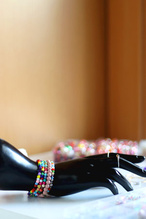 Hand figurine, colorful friendship bracelets, necklaces, various beads and DIY supplies on the table. Making jewelry at home. Selective focus.の写真素材