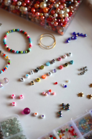 Friendship bracelet spelled with letter beads. Colorful handmade bracelets and various jewelry making supplies. Selective focus, white background.の写真素材
