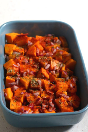 Sheet pan with pieces of butternut squash, onion, herbs and spices. Selective focus.の写真素材