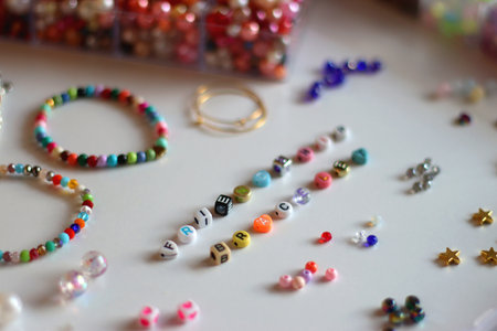 Friendship bracelet spelled with letter beads. Colorful handmade bracelets and various jewelry making supplies. Selective focus, white background.の写真素材