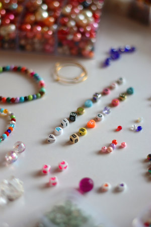 Friendship bracelet spelled with letter beads. Colorful handmade bracelets and various jewelry making supplies. Selective focus, white background.の写真素材